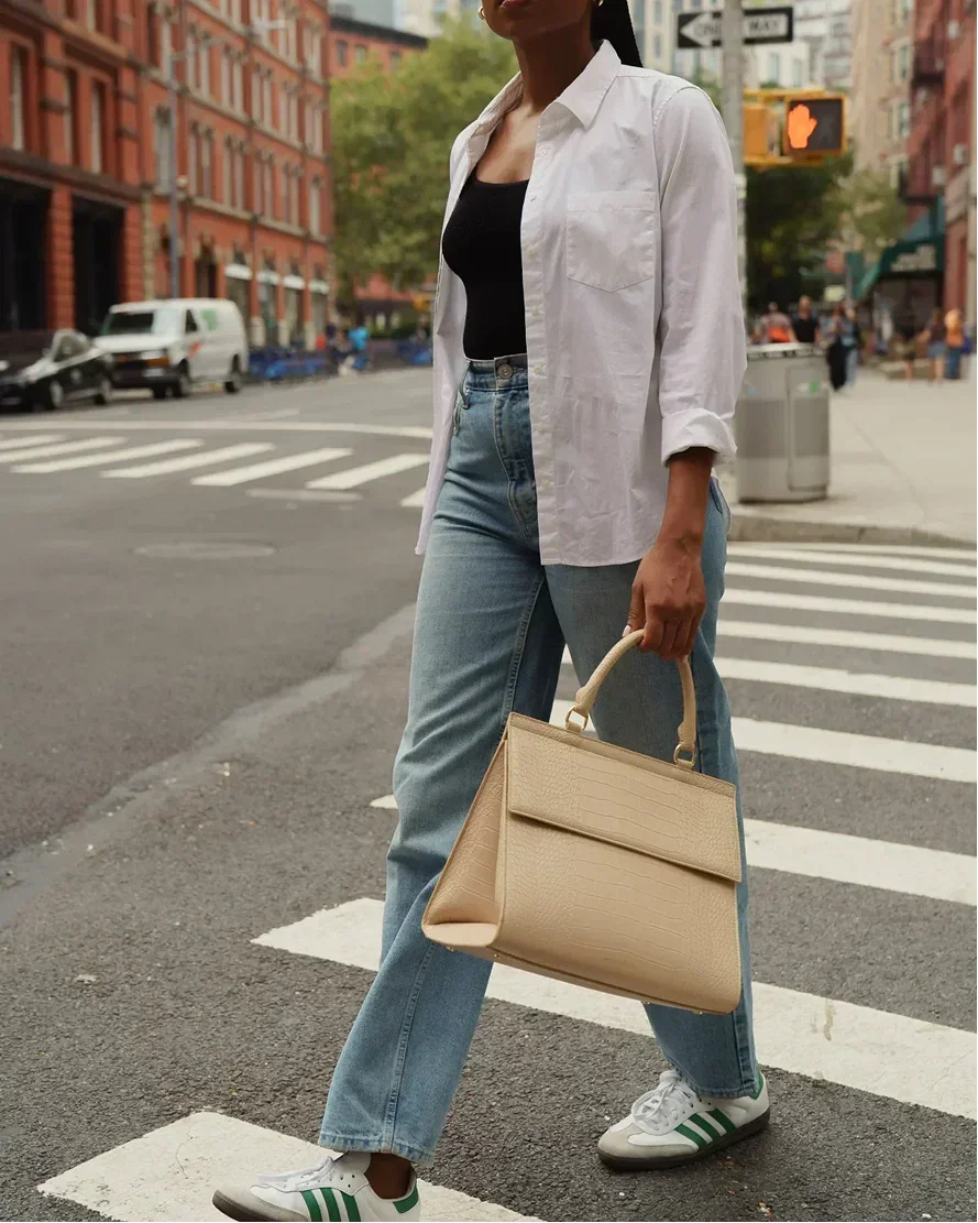 Woman crossing city street holding cream-colored croc-embossed vegan leather lunch bag
