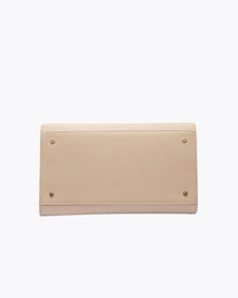 A view of the bottom of the cream-colored handbag, showing the flat base with four small gold metal feet (studs) designed to protect the material.