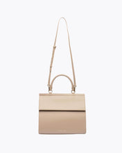 A front-facing studio shot of the cream top-handle handbag hanging from its adjustable, thin shoulder strap. The bag features a flat top flap, a structured shape, and sleek gold hardware.