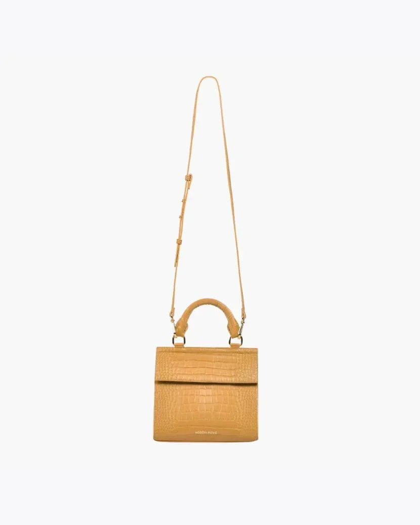 Front view of the Marigold Croc Kids Mini by Modern Picnic, shown with its long adjustable crossbody strap extended. The marigold yellow croc-embossed vegan leather bag features a top handle, structured silhouette, and front flap, displayed on a white background.