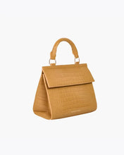 Side angled view of the Marigold Croc Kids Mini by Modern Picnic, showcasing the marigold yellow croc-embossed vegan leather exterior, structured trapezoid silhouette, top handle, and front flap closure on a clean white background.