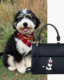 Black and white dog with red plaid bandana beside black insulated vegan leather lunch purse featuring dog illustration