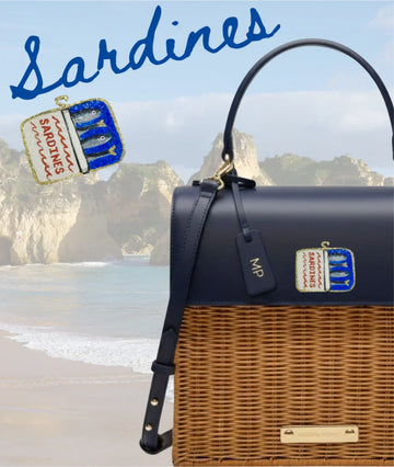 Navy and wicker tote with sardine can patch, beach backdrop, vegan leather lunch bag for stylish picnics
