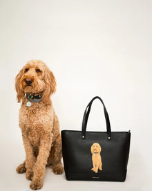 Fluffy golden dog beside black tote with matching dog print, chic vegan leather design