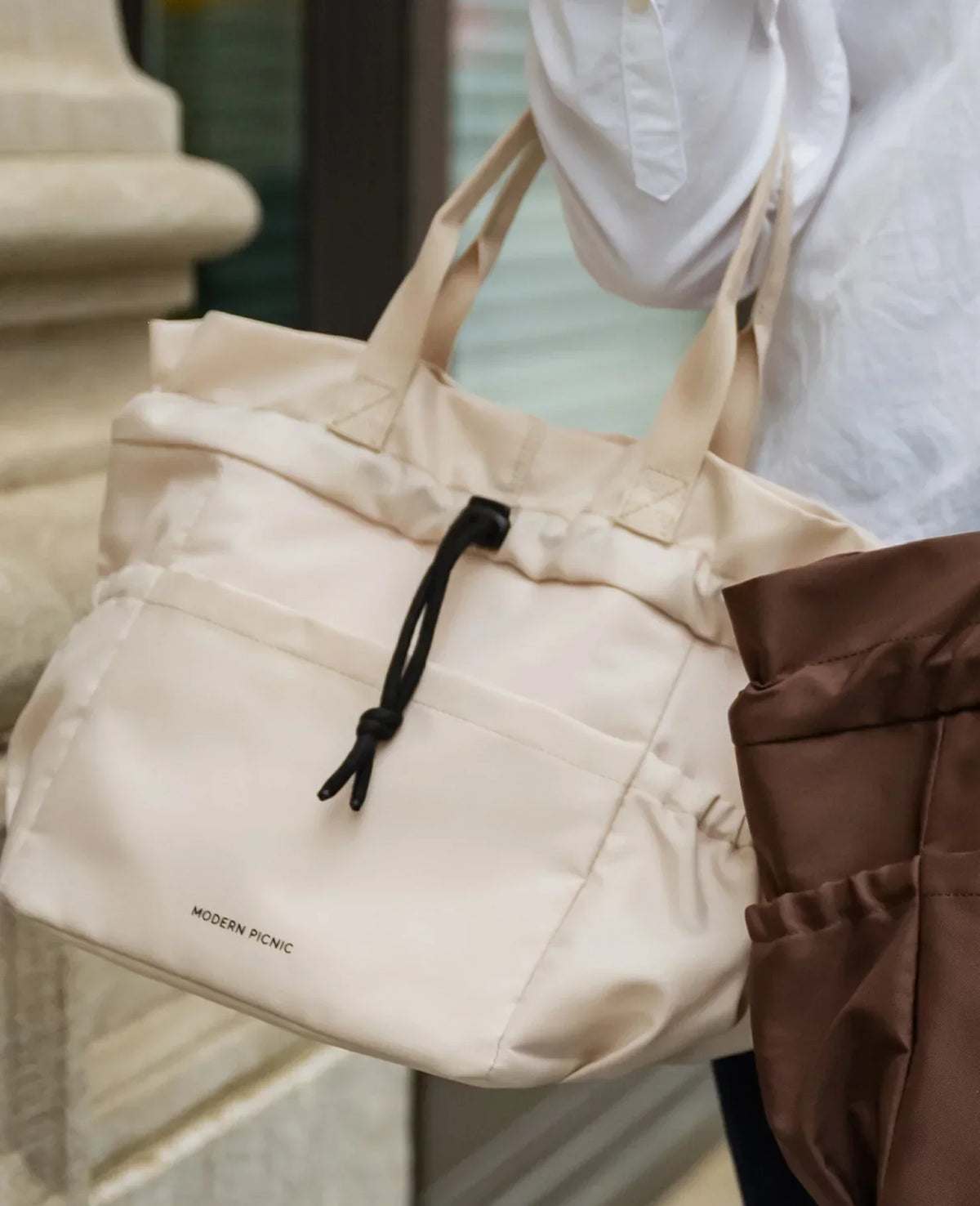 A cream-colored Modern Picnic insulated tote bag with black drawstring detail.