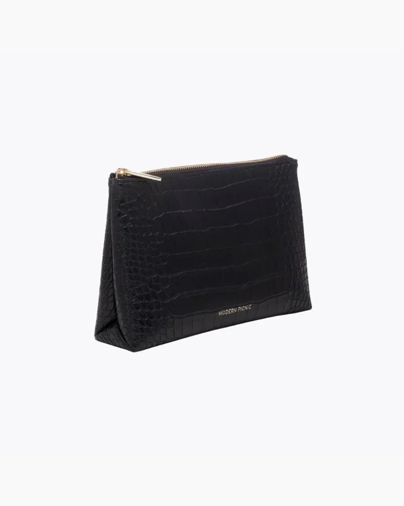 A three-quarter studio shot of a small black zippered pouch with an all-over crocodile-embossed texture. The bag has a gold zipper and a visible gold "MODERN PICNIC" logo along the side base.