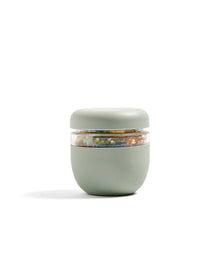 Sage green insulated lunch container with clear seal, filled with salad, modern design
