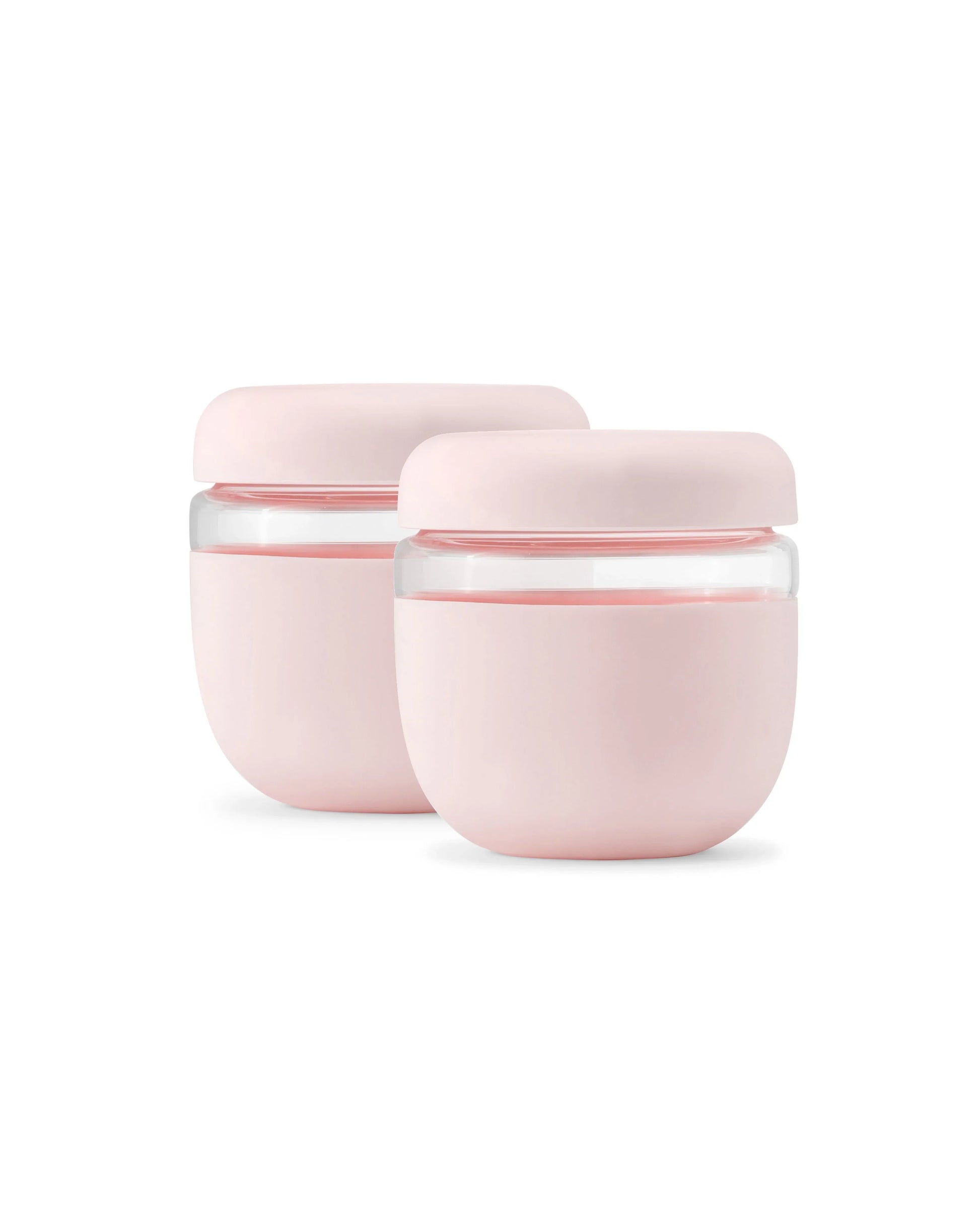 Set of two blush pink, seal-tight glass food containers with rounded lids on white background.