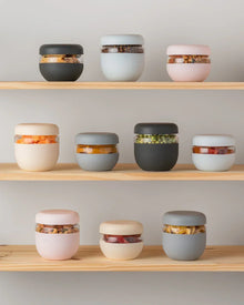 Assorted modern reusable food storage containers with snacks displayed on wooden shelves
