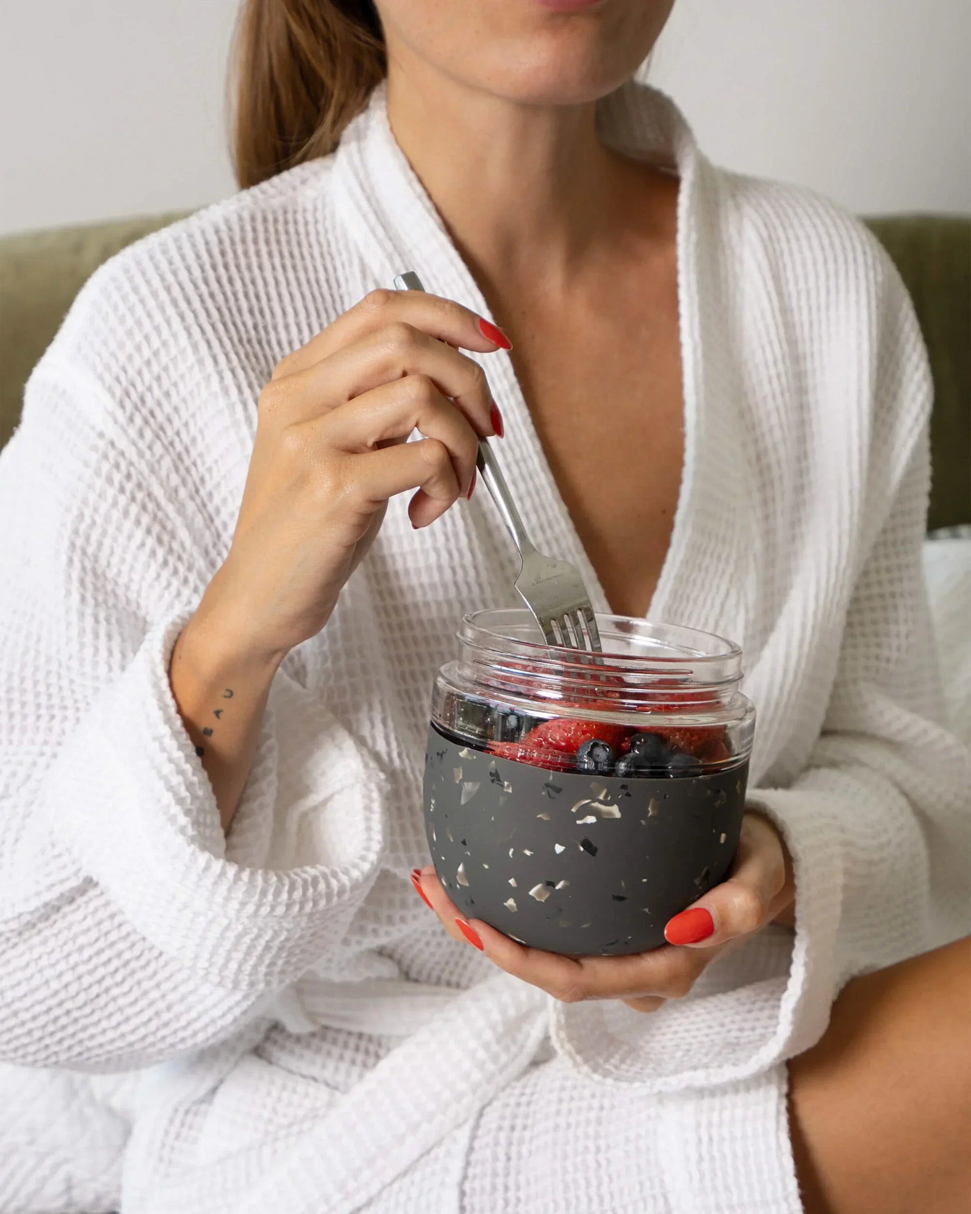 Woman in robe holding a charcoal terrazzo food storage bowl with berries
