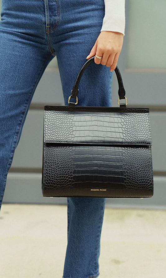 Woman holding the Modern Picnic black croc bag from The Bigger The Better Set by its top handles.
