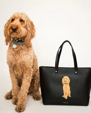 Goldendoodle sitting next to the black Pet Portrait Snacker pouch and Pet Portrait Tote bag.	