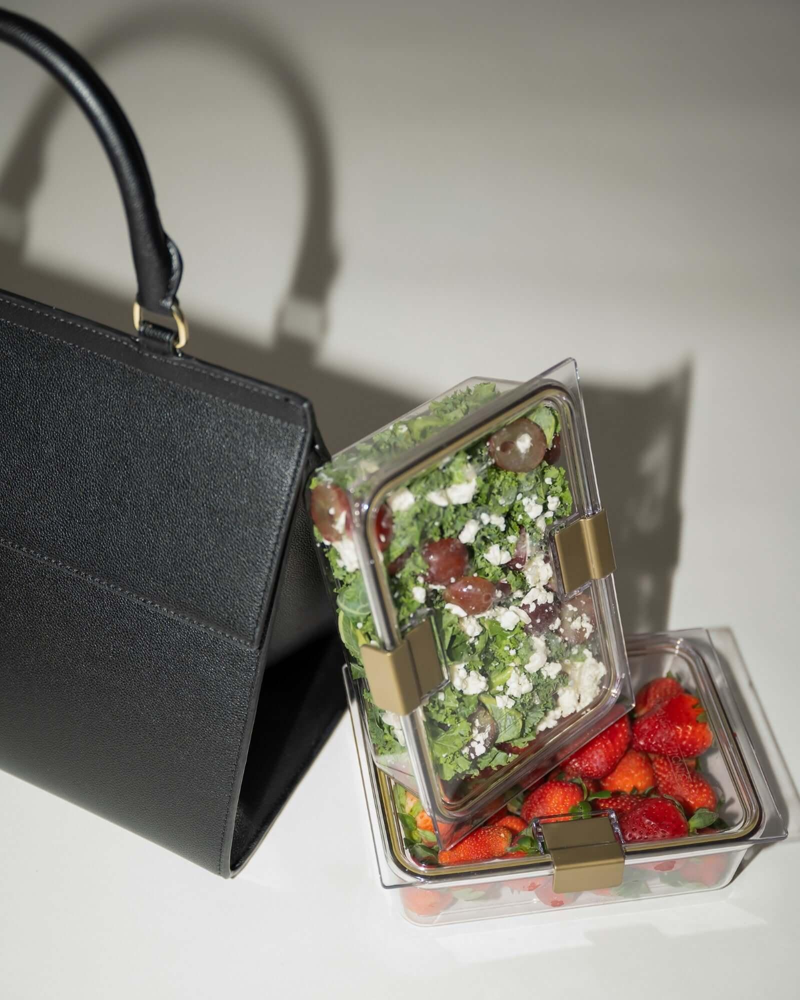 Black large luncher bag with food containers filled with healthy meals and fresh ingredients