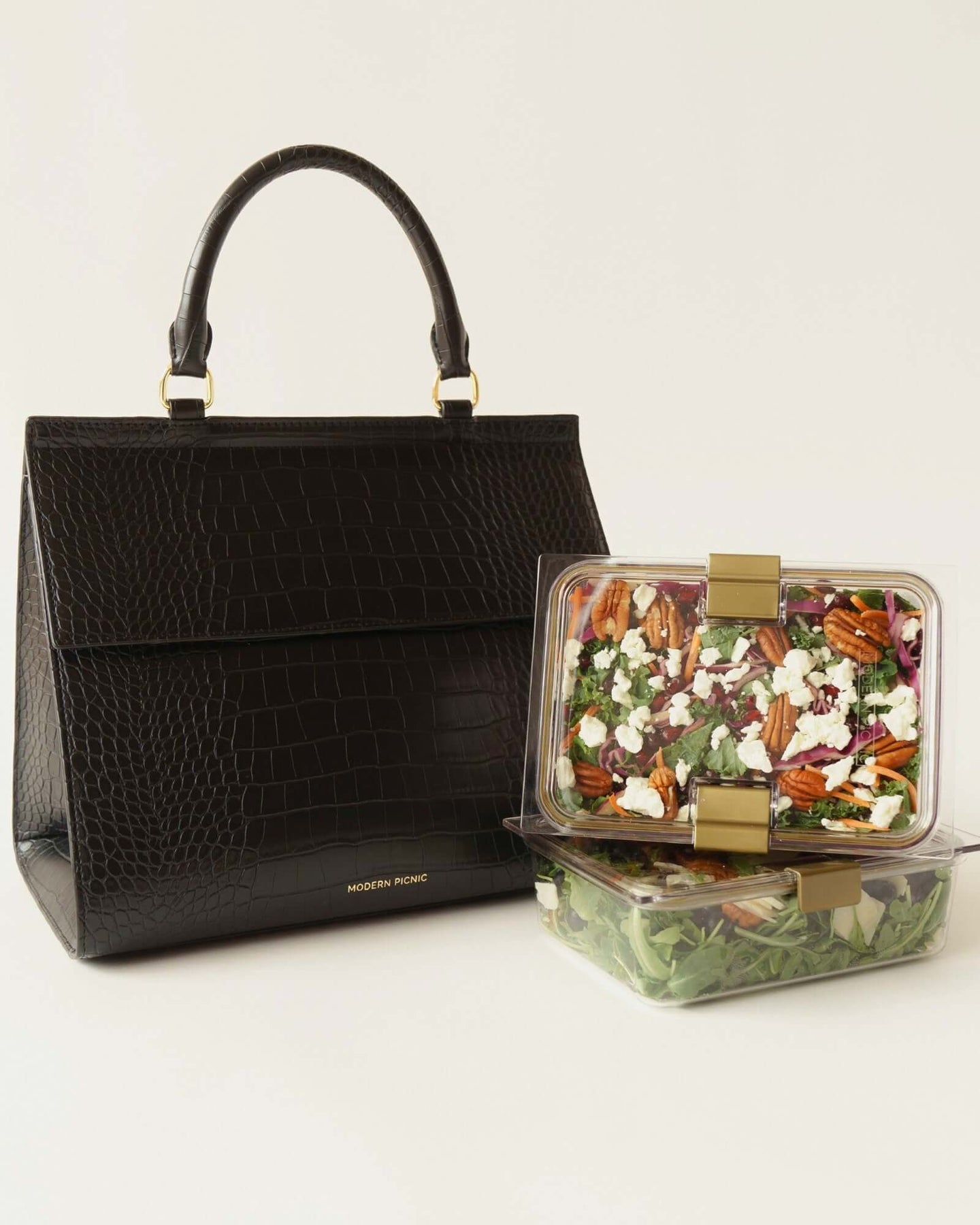 Black large luncher bag with two reusable food containers filled with salad and fruit