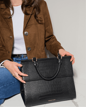 Person placing The Large Luncher - Black Croc on a table, showing practical size and elegant look.