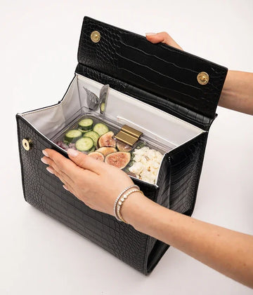 Open black vegan leather insulated lunch bag containing a meal prep container with fresh food.