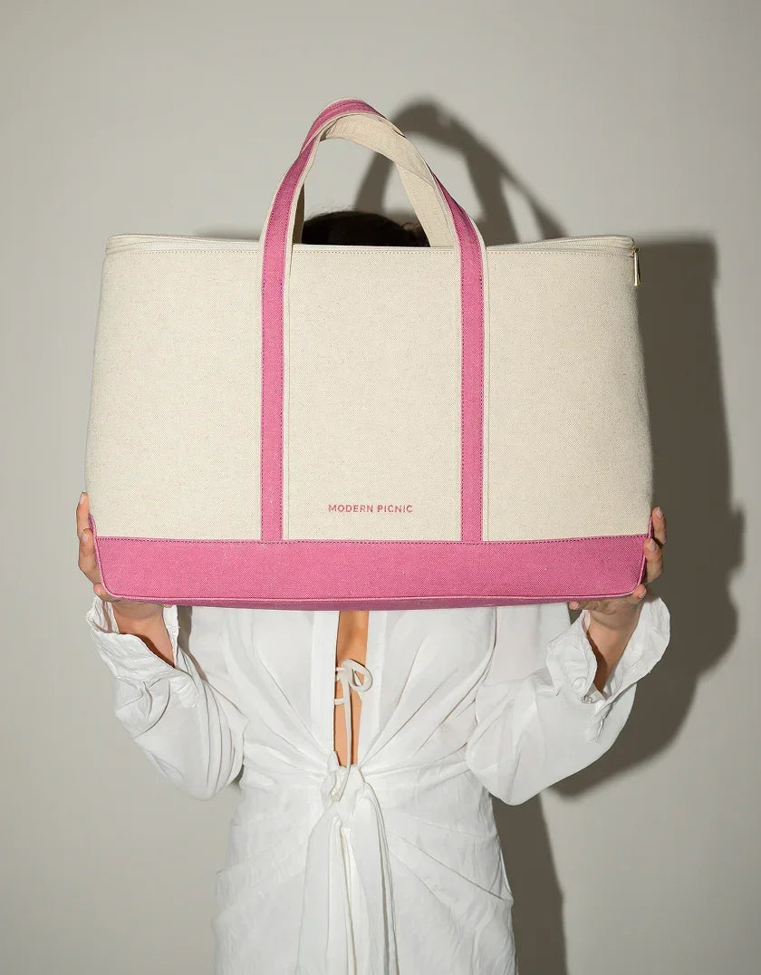 Chic beige and pink insulated tote bag held by woman in white dress against neutral background