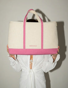 Chic beige and pink insulated tote bag held by woman in white dress against neutral background