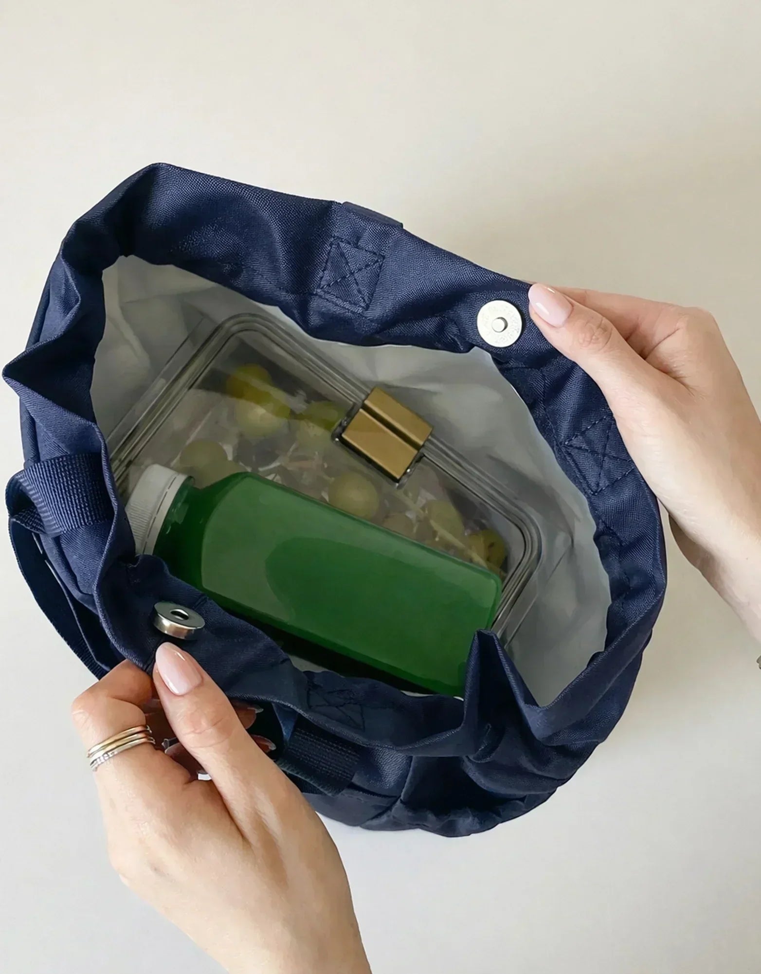 Navy insulated lunch bag with green juice bottle and food container, perfect for work or travel