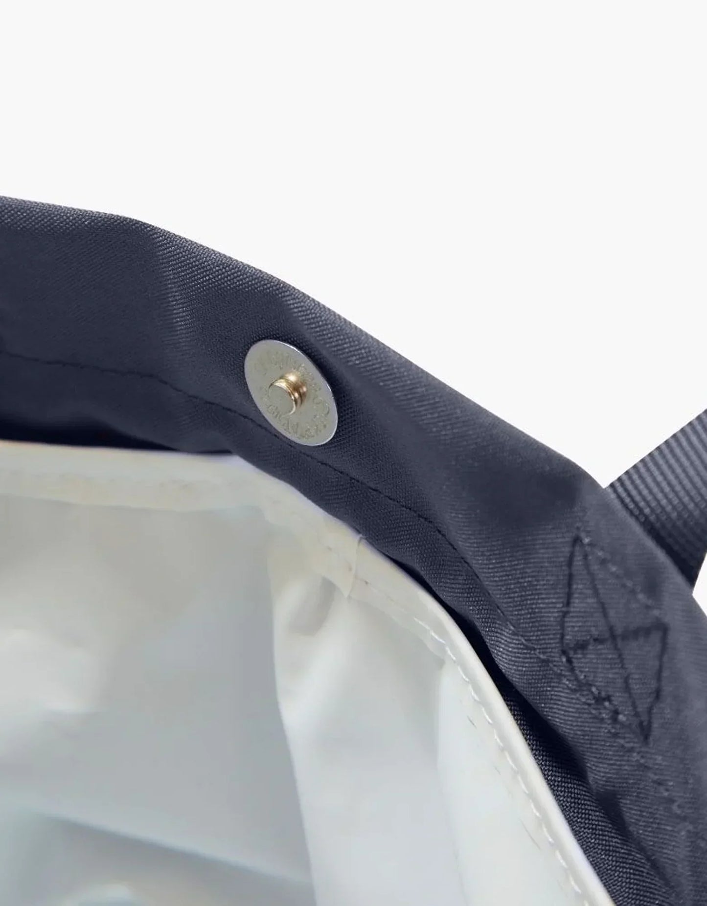 Close-up of navy lunch bag with gold snap button and white insulated interior, chic vegan leather design