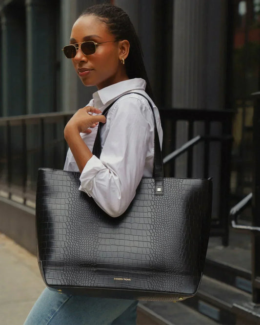 Woman carrying Modern Picnic black croc tote bag over shoulder while walking outdoors