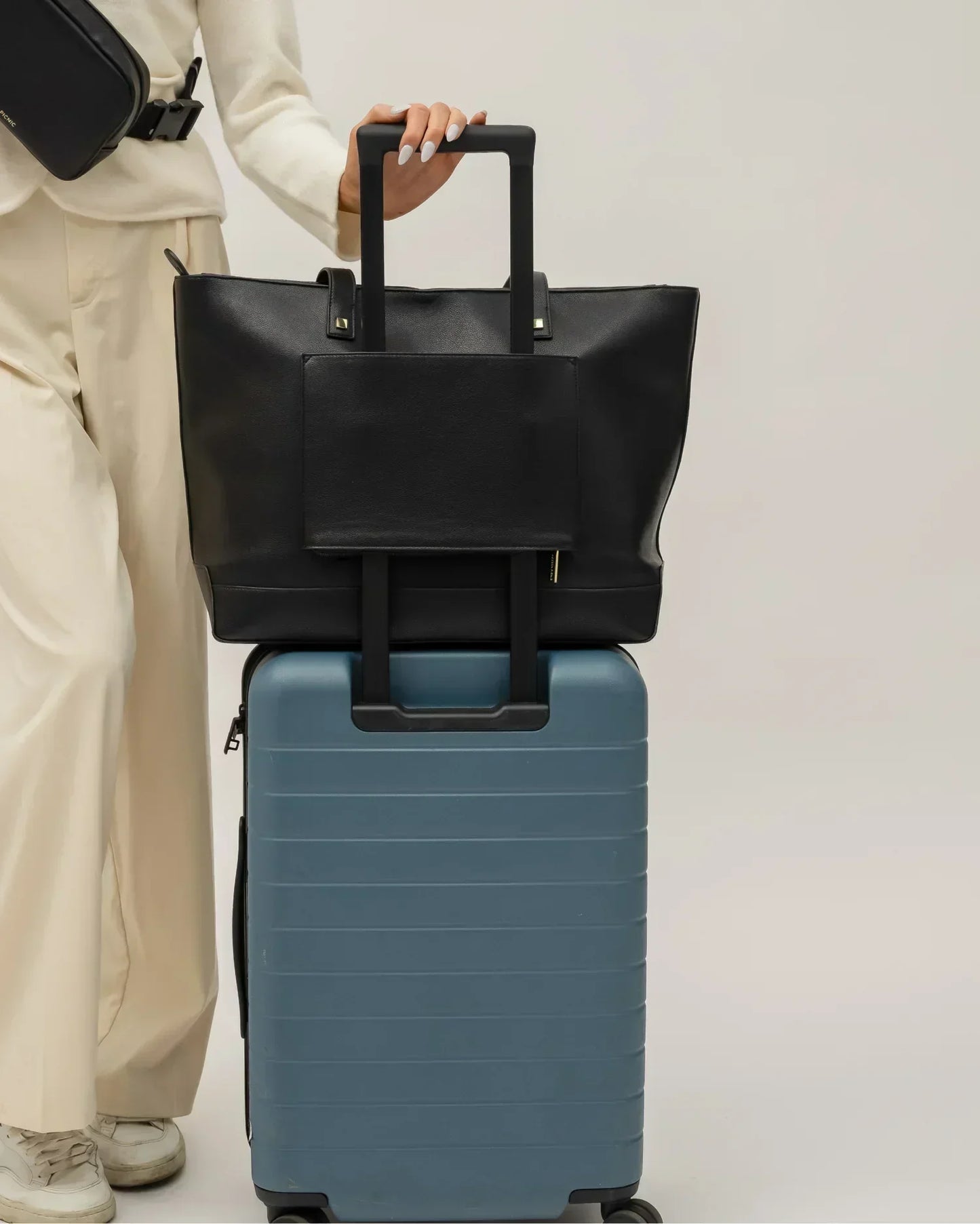 Modern Picnic black pebble tote bag secured on luggage handle, ideal for travel