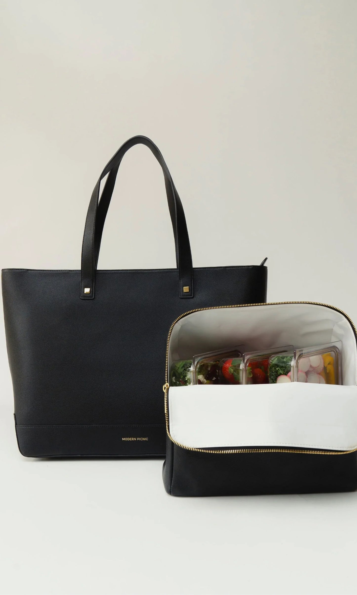 Modern Picnic black tote and croc bag from The Bigger The Better Set, with food containers displayed inside the tote.