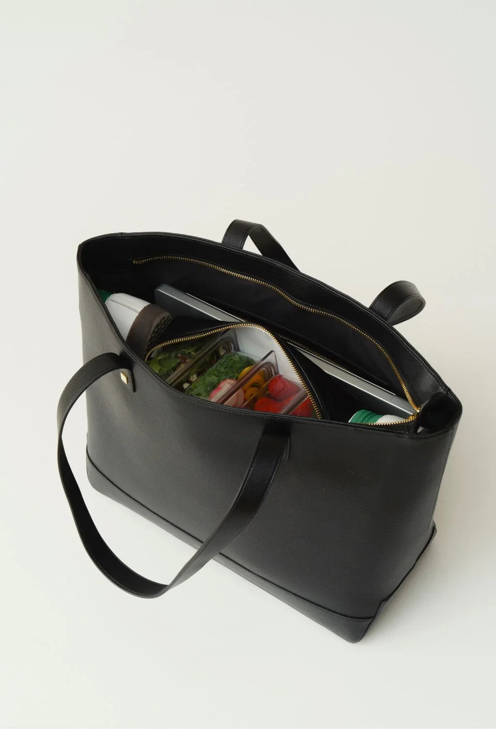 Modern Picnic black tote bag open on a white background, revealing food containers neatly organized inside.
