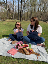 Mother and daughter enjoying a picnic outdoors with their Modern Picnic Mommy and Me Set bags beside them.