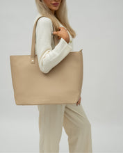 Woman carrying Modern Picnic tote in cream vegan leather over her shoulder in a neutral studio setting.