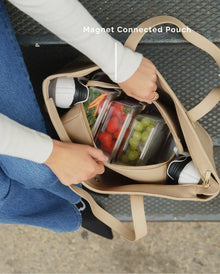 Woman opening Modern Picnic tote in cream vegan leather to access insulated magnetic pouch inside.