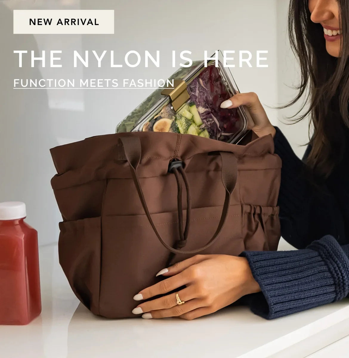 A woman placing a clear glass container filled with salad into a brown nylon insulated lunch tote bag.