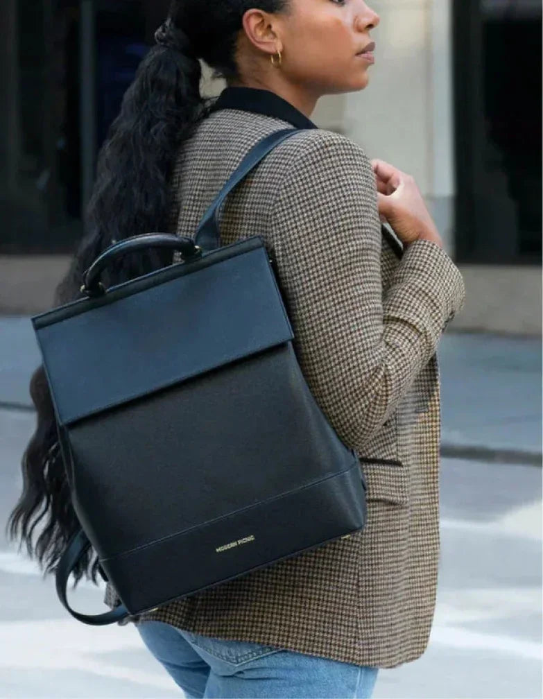 Woman wearing a professional brown checkered blazer and a black vegan leather backpack.