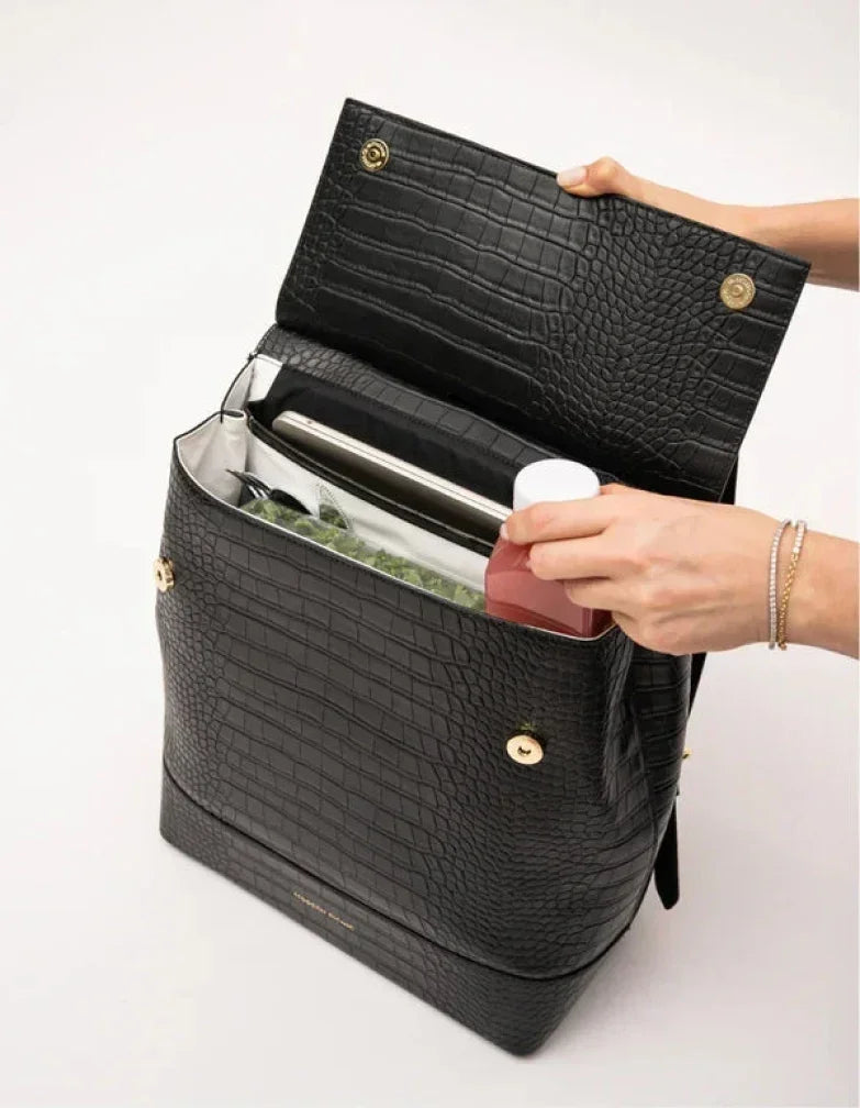 Hands placing a red water bottle into a black croc-embossed insulated lunch bag.