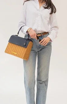 Woman carrying a chic two-tone vegan leather insulated lunch tote in navy and tan.