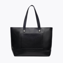 A back-facing studio shot of a large black tote bag with two shoulder straps. The back panel features a stitched-in slip pocket made of pebbled vegan leather.