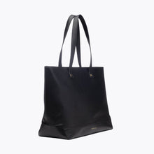 A three-quarter studio shot of a structured, large black tote bag made of pebbled vegan leather. The bag has two tall shoulder straps and subtle gold hardware.